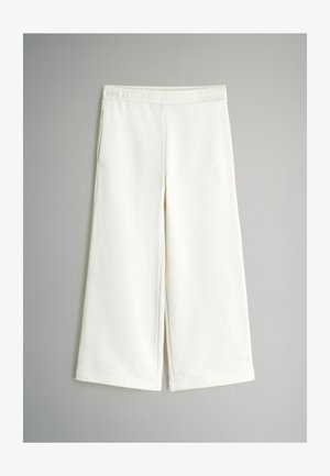 Fehér, bő szárú nadrág, puha anyagból készült, rugalmas derékkal és oldalsó zsebekkel, sima textúrával és letisztult vonalakkal.
