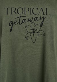 Olivově zelené tričko s černým textem "TROPICAL getaway" a květinovou grafikou lilie. Měkká látka, volný střih, krátké rukávy.
