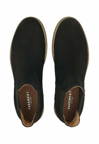 Bottines noires en suede avec panneaux élastiques sur les côtés, semelle beige et bout rond. L'intérieur présente un doublure marron et un logo en relief.