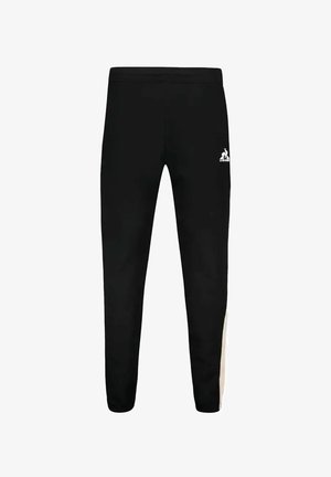 Pantalones de chándal negros ajustados con un logo blanco en el muslo izquierdo y un panel beige en contraste en el costado. Hechos de una tela suave y elástica.