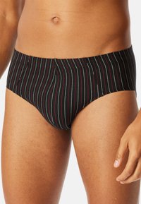 Caleçons noirs à rayures avec des rayures verticales rouges et blanches, une texture de tissu douce et un design ajusté avec une taille mi-haute.