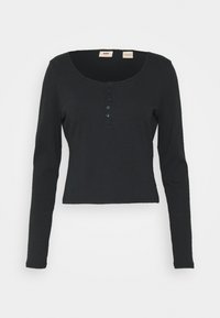 Top nero a maniche lunghe in materiale a coste, con scollatura a barchetta e bottoni lungo la parte frontale. Design aderente, lunghezza cropped.