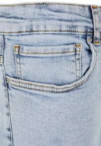 Világoskék farmernadrág, hátsó zsebbel, kontrasztos narancssárga varrással és enyhén megfakult textúrával.