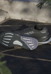 Donkergrijze sportschoenen met een bovenwerk van gestructureerde stof. Voorzien van een patroonrubber loopzool en een lichtgrijze tussenzool met duidelijke profielen.