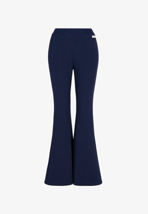 Granatowe, z wysokim stanem, rozkloszowane spodnie z szerokim elastycznym pasem i małą białą metką marki w pobliżu prawego biodra.