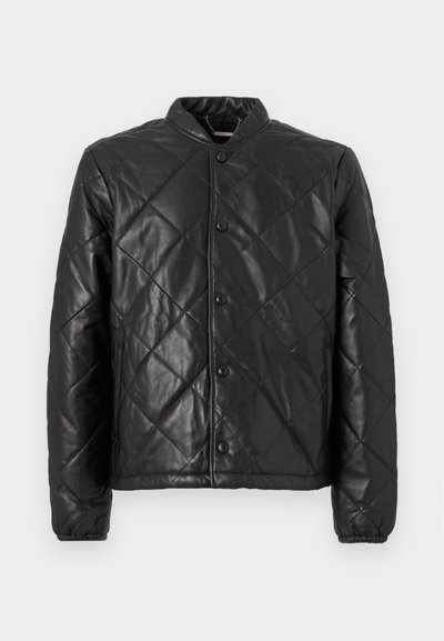 Μαύρο καπιτονέ μπουφάν από δέρμα, με στρογγυλή λαιμόκοψη, κουμπιά με κλιπ και ελαστικούς λεπτομέρειες στα μανίκια. Η επιφάνεια έχει λεία υφή με διαμαντέ σχεδίο.