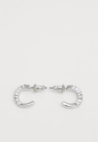 Orecchini ad anello in argento caratterizzati da un design curvato lucido con accenti scanalati e perni metallici per una chiusura sicura.