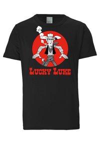 Musta puuvillapaita, jossa on sarjakuvahahmo punaisessa ympyrässä, tupakoimassa pääkallodekaation kanssa. Teksti lukee "LUCKY LUKE" paksuilla punaisilla kirjaimilla.