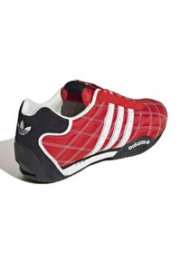 Röd och svart sneaker med kviltat mönster, vita accenter och tre ränder. Har en rund tå och texturerad gummisula.