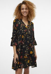 Vestido preto floral com um design em camadas, apresentando mangas franzidas e padrões florais vibrantes em amarelo, vermelho e rosa por todo o tecido.