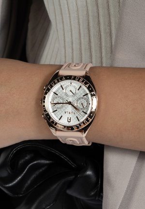 Orologio Furla con una cassa dalla finitura argentata, cinturino in silicone rosa e bezel in oro rosa con lettering nero. Sottodial e logo visibili.