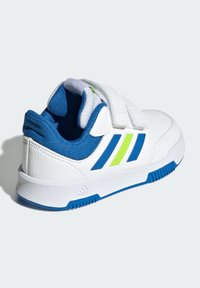 Baltas sporta apavus ar zilu un laima zaļu akcentu. Iezīmējas ar strukturētu sintētisku augšdaļu un drošiem Velcro siksnām aizdarei.