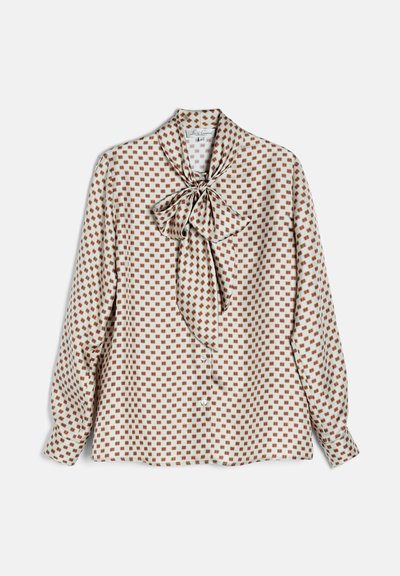 Blouse blanche à manches longues avec motif carré marron et un grand nœud noué au niveau du col, présentée à plat.