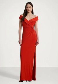 Vestido rojo sin mangas con un escote asimétrico, diseño hasta el suelo, abertura lateral y textura suave. Ideal para ocasiones formales.