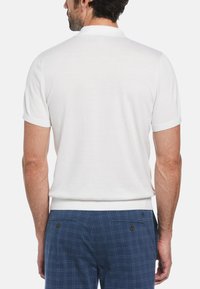 Weißes Poloshirt mit kurzen Ärmeln, geripptem Kragen und Bündchen, mit glatter Textur und lässigem Schnitt. Kombiniert mit navyblauen karierter Shorts.