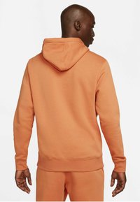 Felpa con cappuccio in morbido tessuto di spugna, di colore arancione, con tasca a marsupio e polsini e orlo a coste.