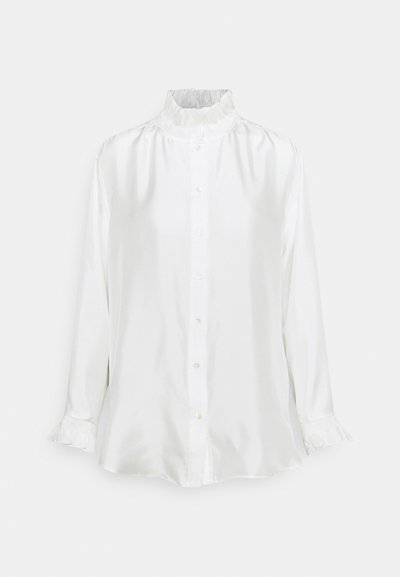 Chemise en satin blanc avec un col à volants haut, des manches longues avec des poignets à volants et une fermeture à boutons sur le devant. Texture lisse avec une coupe décontractée.