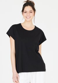 Black short-sleeve t-shirt with a round neckline and relaxed fit. Made of soft fabric with subtle texture, displayed with neutral pants.