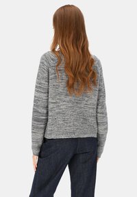 Szary dzianinowy sweter o teksturowanym wykończeniu i długich rękawach, charakteryzujący się luźnym krojem i ściągaczem na dole, zestawiony z ciemnymi spodniami z denimu.