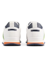 Baskets blanches avec des accents marine, des panneaux latéraux verts, une semelle intermédiaire orange et un cuir texturé au niveau du talon. Dotées d'une languette à l'arrière.