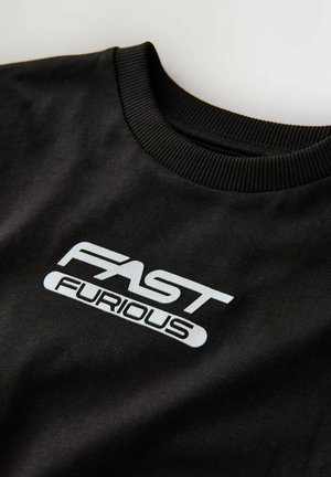Musta lühikeste varrukate koolisärki, mille rinnal on julge, stiliseeritud valge kiri "FAST FURIOUS".