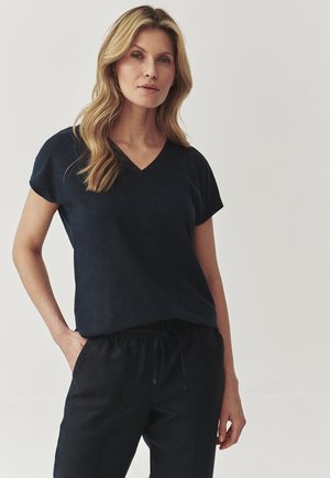 Donkerblauw V-hals T-shirt met korte mouwen, met een relaxte pasvorm en een zachte textuur. Gecombineerd met zwarte broek met elastische taille.
