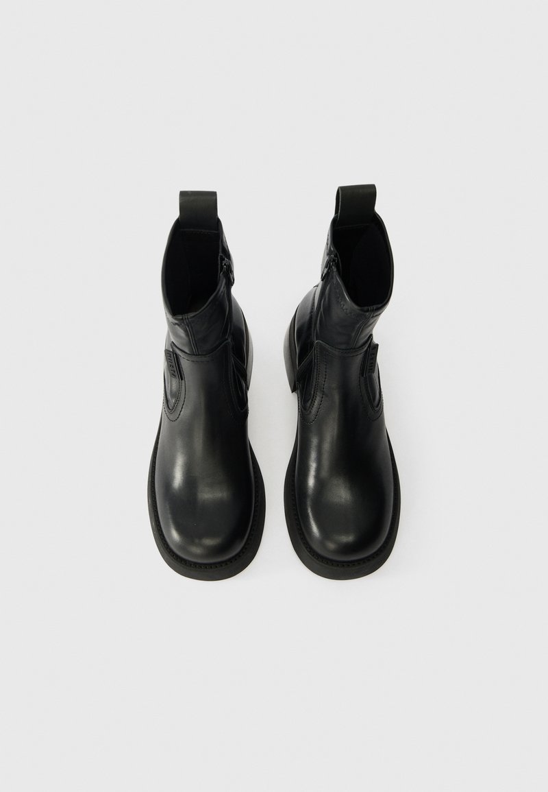 Sæt af sorte læder ankelstøvler med runde tæer og sidelukninger, vist ovenfra på en hvid baggrund.
