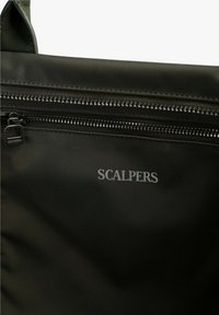 Bolsa de tela negra con una gran cremallera y el logo "SCALPERS" en gris. La superficie tiene una textura suave con un acabado mate.