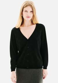 Cardigan en maille noire avec un décollet�é en V profond, des manches longues et une fermeture à boutons. Présente un motif en losange avec une texture subtile tout au long.