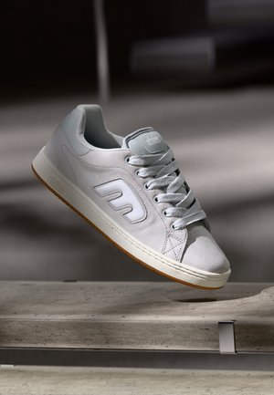 Heledad hall suede toss sa valgete detailidega, ümar varvas, pehmendusega krae ja tekstureeritud kummist talla. Omab logo külgedel ja paelu.