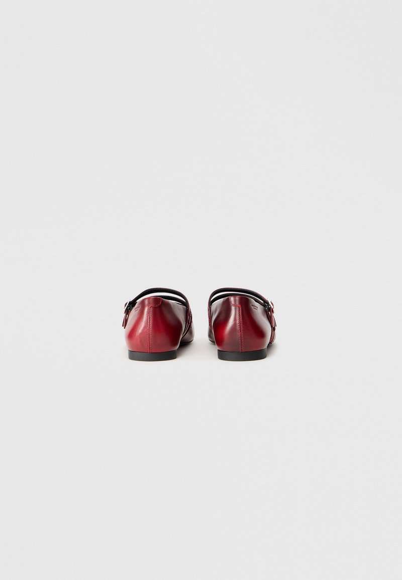 Rote Leder-Ballerinas mit runder Spitze, niedrigem Absatz und schwarzer Zierkante. Besitzen eine dekorative Schnalle an der Seite und eine glatte Oberfläche.