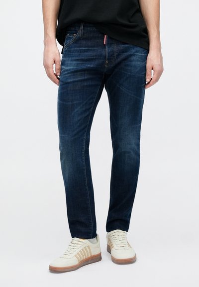 Sötétkék farmernadrág karcsúsított szabással, közép magas derékrésszel, ötlukú zsebes kialakítással és finom kifakulással a lábakon.