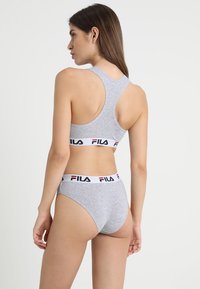 Sportivo grigio in cotone con dettagli del logo FILA in bianco, rosso e blu, abbinato a slip con fascia in vita; design a racerback, texture morbida.