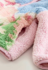 Bunt gemusterte Fleece-Decke mit rosa, blau, grün und cremefarbenen Texturen. Weiche, flauschige Oberfläche mit einem kuscheligen, angenehmen Gefühl.