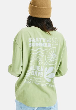 Chemise verte à manches longues en tissu doux, ornée de texte graphique blanc et de motifs tropicaux, comprenant des vagues et des feuilles au dos.