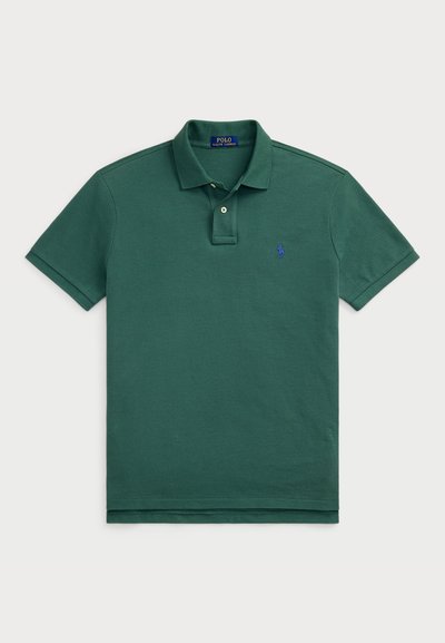 Zelena polo majica iz bombaža, s tri gumbe na zapenjanju, kratkimi rokavi in majhnim modrim logotipom na levem prsnem delu.