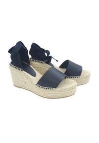 Sandalias de cuña en azul marino con una correa ancha y suave y suela de yute trenzado. Presentan lazos de tela texturizada en el tobillo para un ajuste seguro.