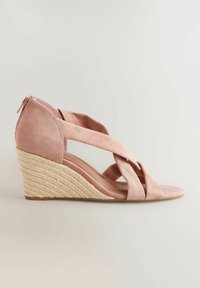Sandalo con zeppa in suede rosa pallido con fasce incrociate e tacco avvolto in juta. Presenta una cerniera sul retro per una facile vestibilità.