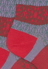 Colorful knitted socks featuring a mix of patterns: red, green, and purple motifs; textured sections; smooth toe and cuff areas.