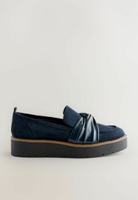 Navy suede slip-on shoe with a gloss black bow accent, featuring a thick black platform sole and rounded toe design.