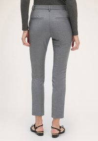 Dopasowane szare spodnie, slim fit, gładka tekstura, dwie tylne kieszenie i długość do kostek. Zestawione z czarnymi sandałami z akcentem w postaci klamry.