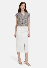 Zwart-wit gestreepte blouse met korte mouwen, gecombineerd met een witte spijkerrok tot de knie met een split aan de voorkant. Eenvoudige hoge sandalen.