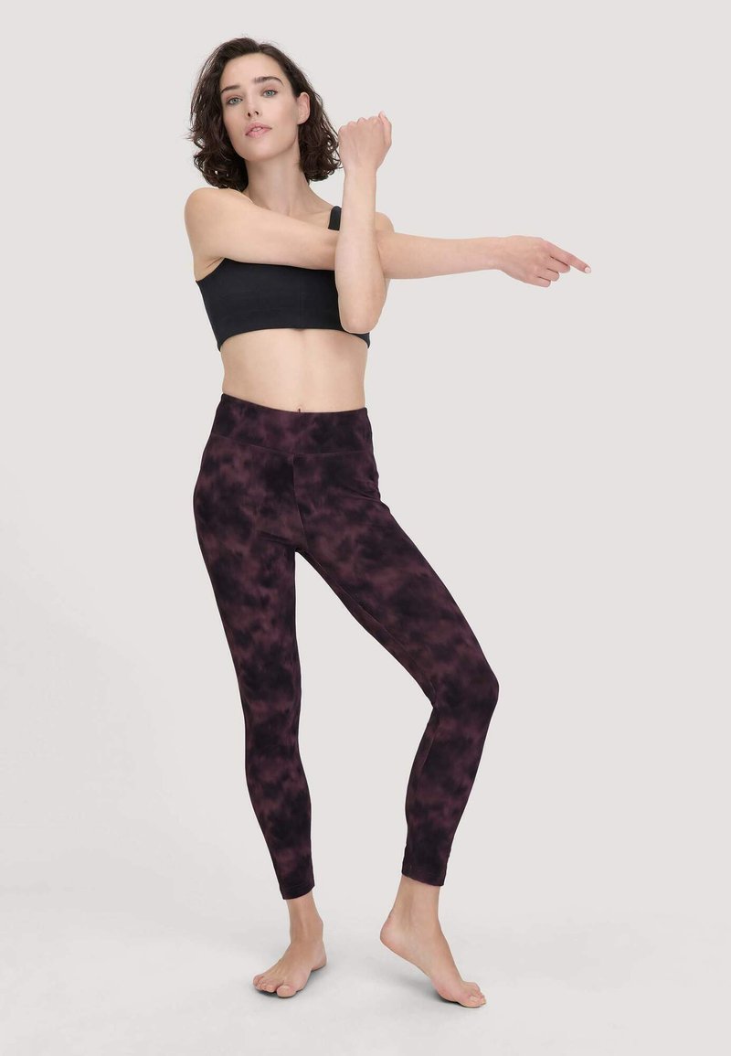 Zwarte sportbeha met paarse tie-dye leggings, rekbare stof, hoge taille, soepele textuur, aangesloten design en enkel-lengte stijl.