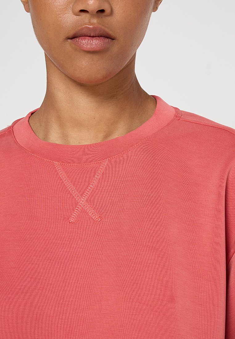 Korallfarbene Baumwoll sweatshirt mit einem runden Ausschnitt und gekreuzten Nähten am Kragen. Glatte Textur und lässige Passform.