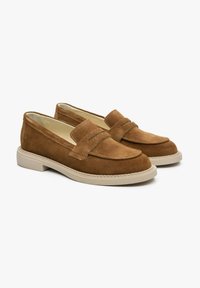 Brązowe zamszowe loafersy z zaokrąglonym noskiem, dekoracyjnym przeszyciem i jasnobeżową gumową podeszwą. Model charakteryzuje się klasycznym stylem wsuwanego obuwia.