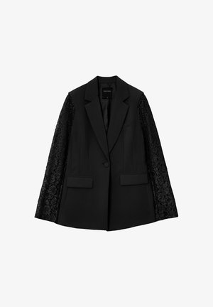 Blazer nero con corpo in tessuto solido e maniche in pizzo. Dettagli notevoli includono due tasche frontali e una chiusura a un pulsante.