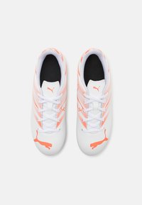 Scarpe da ginnastica bianche con accenti arancioni. Presentano un design strutturato, punta tonda e chiusura con lacci. Logo visibile sui lati.