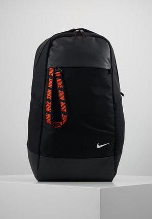 Schwarzer Rucksack mit matter Oberfläche, der ein strukturiertes Hauptfach, einen orangefarbenen Markenriemen und ein weißes Nike-Logo an der Basis aufweist.