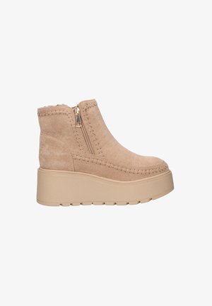 Botas de tobillo de ante beige con suela de plataforma, cierre lateral con cremallera y costuras decorativas a lo largo de los bordes. Forro interior de textura suave.