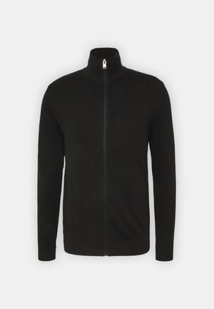 Suéter negro con cremallera y cuello alto, de mangas largas, con puños y dobladillo acanalados. Fabricado en una tela suave con una textura lisa.